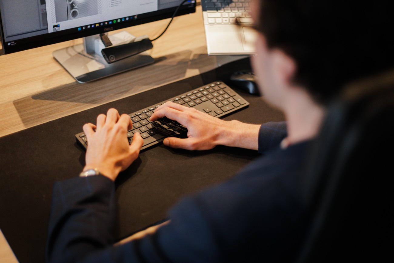 Een stagiair aan het werk achter de computer op het kantoor van Stigo